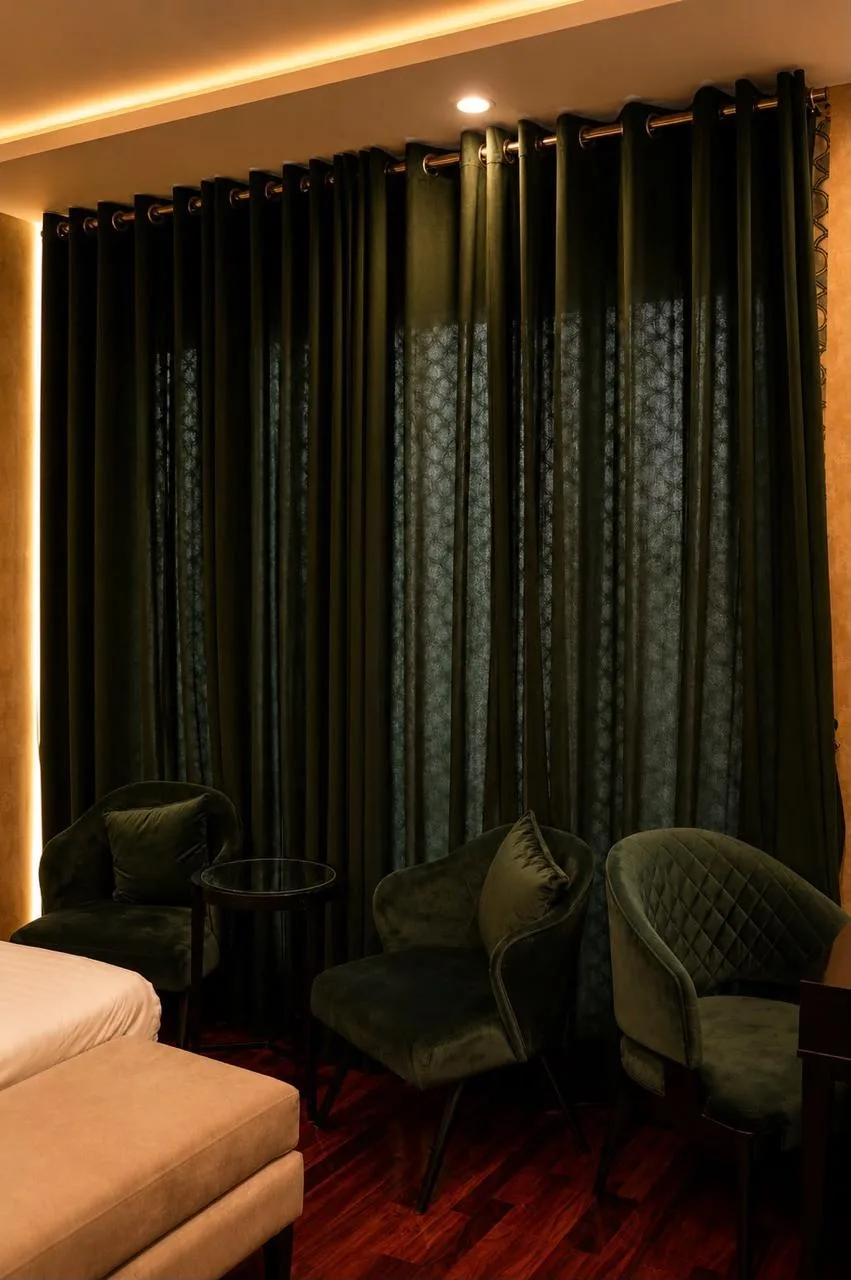 Velvet armchairs beside floor-length emerald curtains in the Presidential Suite